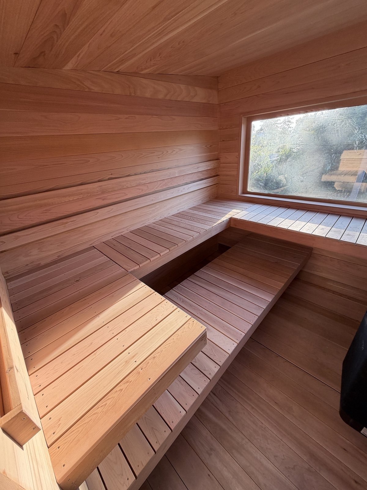 Pale cedar sauna interior with a window, built for a Berkeley home